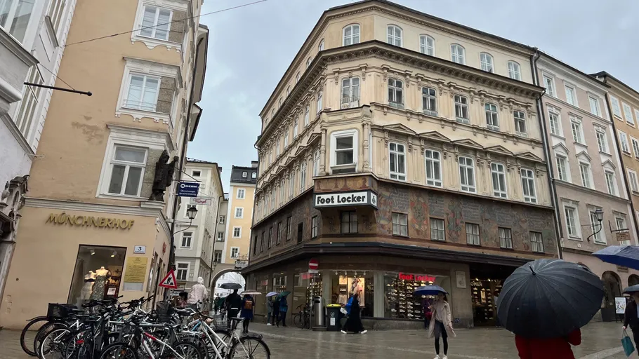 Leute mit Regenschirmen in verregneter europäischer Stadt.