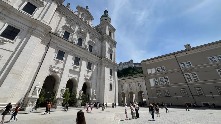 Personen spazieren vor einem großen historischen Gebäude.