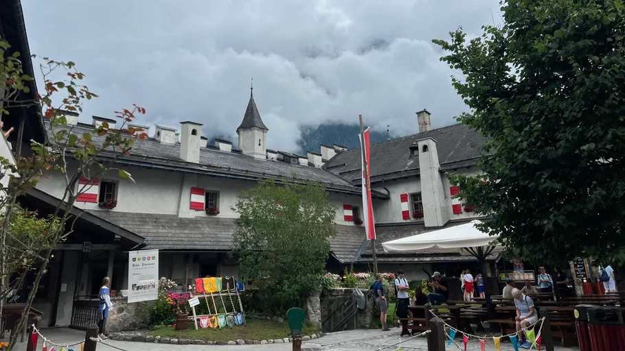 People gather in courtyard beneath cloudy mountain.