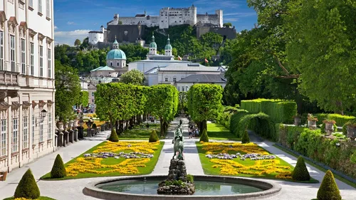 Gardens with castle and mountains in background.
