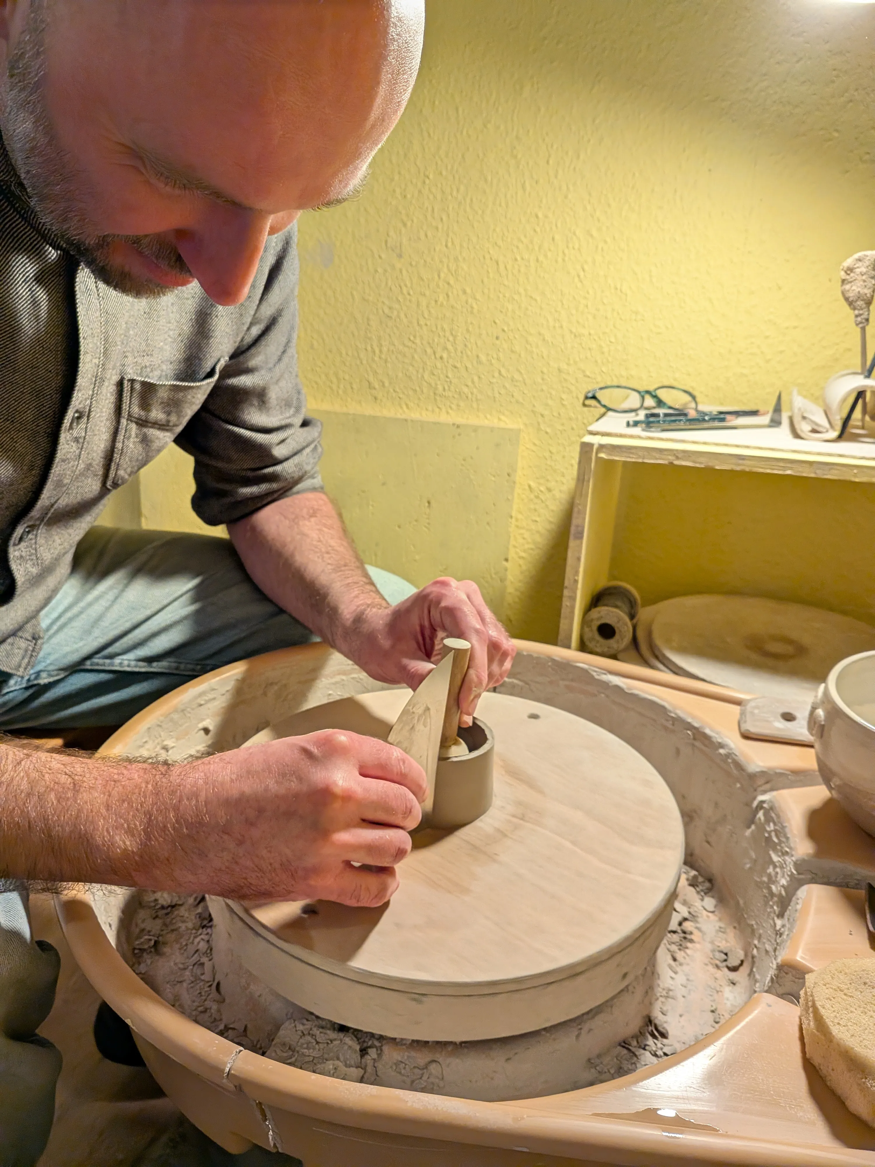 Mann formt Ton auf Töpferscheibe drinnen.