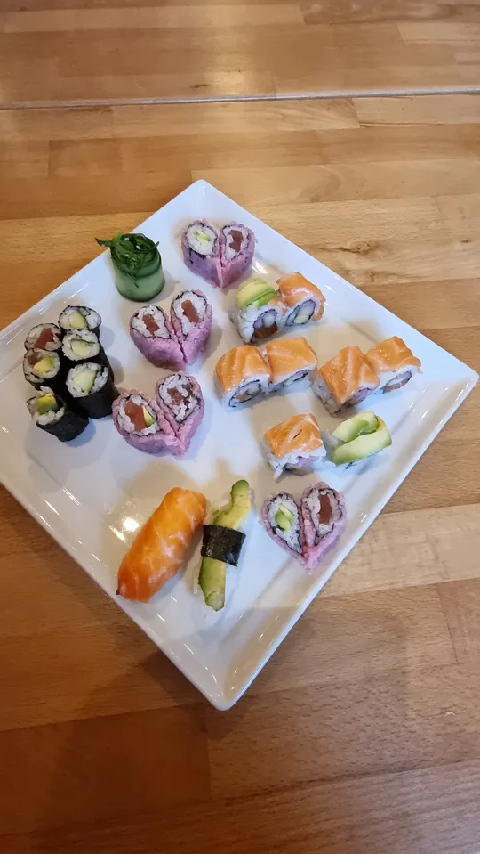Verschiedene Sushi-Rollen auf einem weißen, quadratischen Teller.