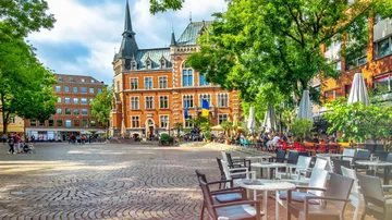 Historic building and outdoor café on a cobblestone square.