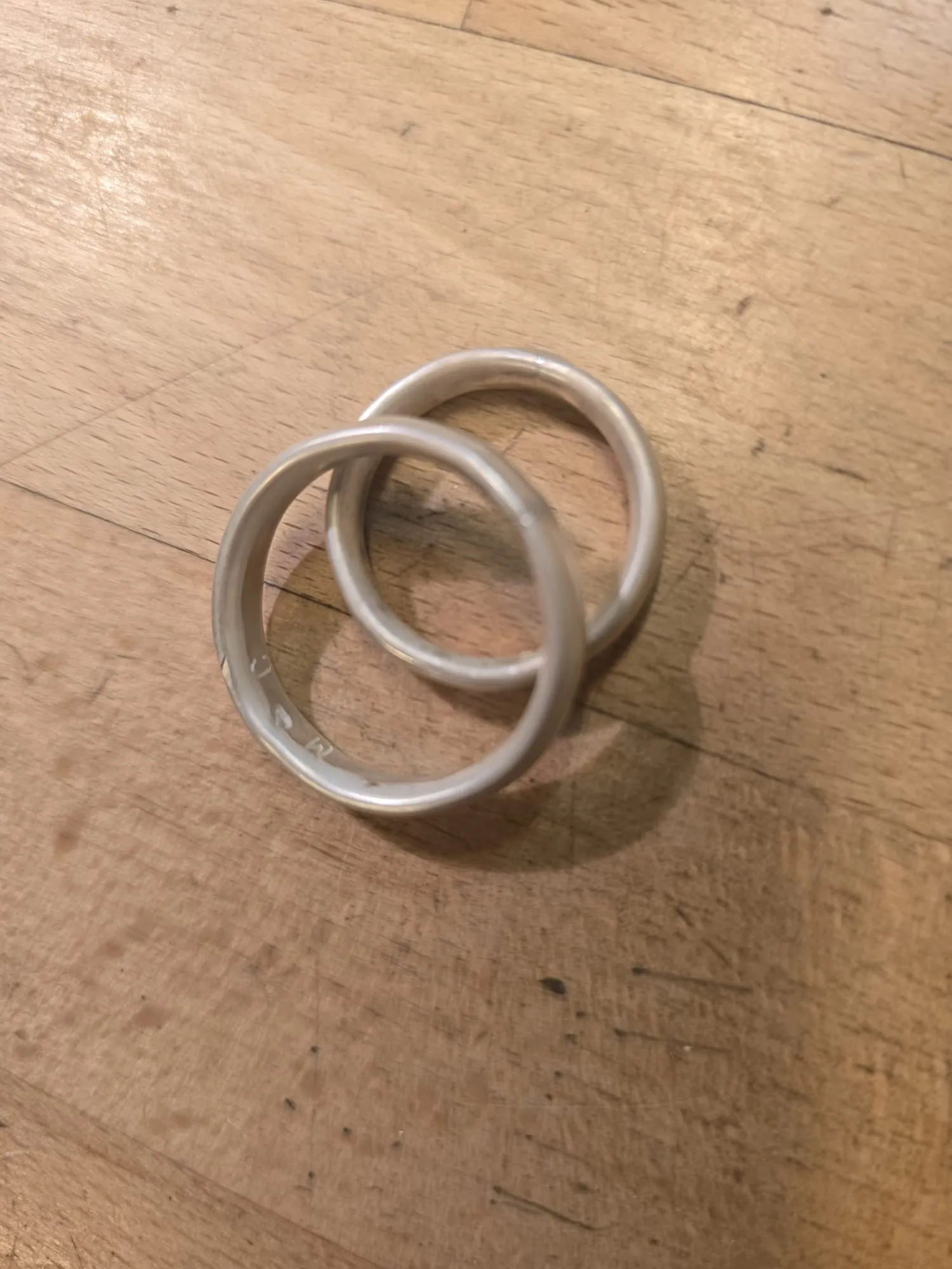 Zwei Kunststoffringe überlappend auf Holzoberfläche.