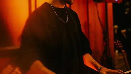 Person playing keyboard in dimly lit room.