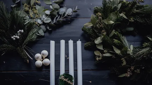 Candles and wreath on dark wooden table.