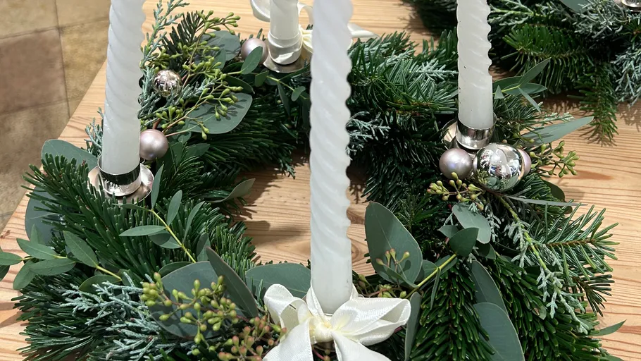 Advent wreath with white candles on wood table.