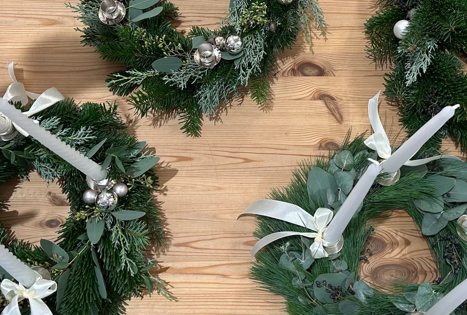 Decorative wreaths with candles on wooden table.