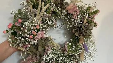Blumenkranz vor weißem Hintergrund gehalten.