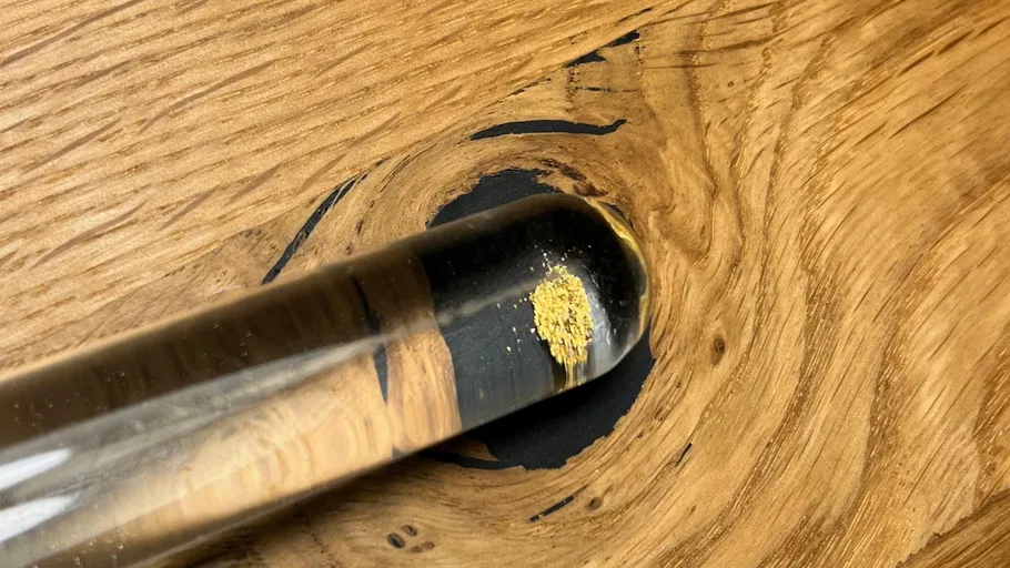 Test tube with yellow powder, wooden background.