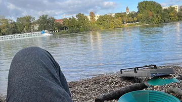 Riverbank view with city, pans, and person.