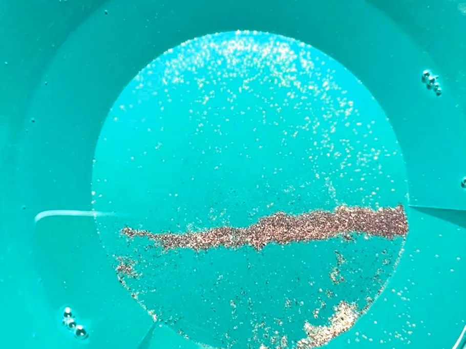 Gold flakes in a green pan.