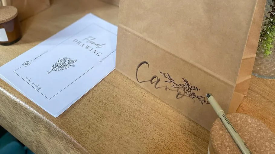 Papiertüte mit Blumendesign auf Tisch.