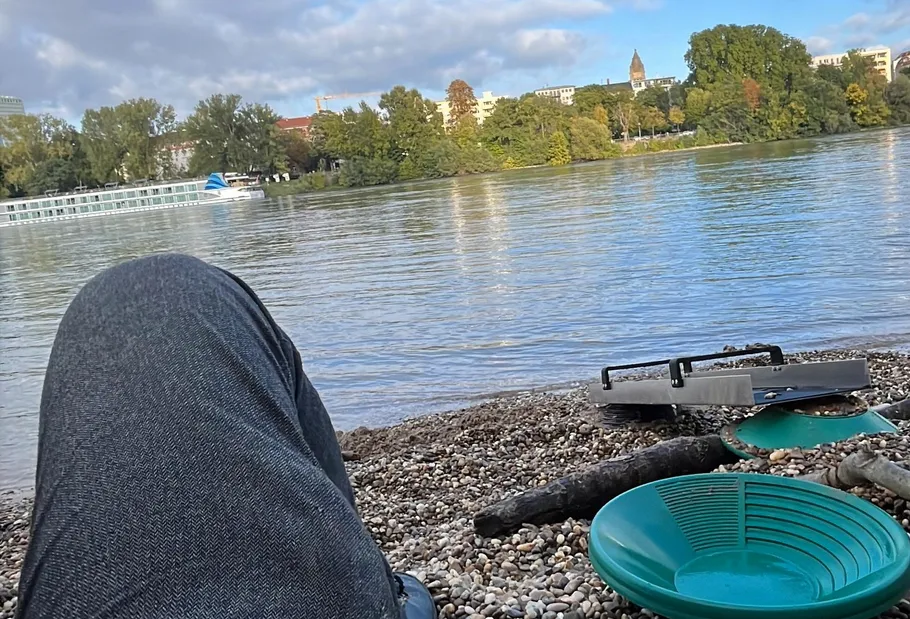 Person relaxing by a river with gold pans.