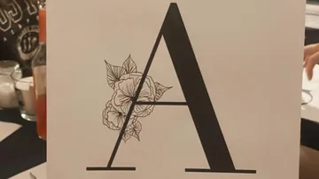 Large letter 'A' with floral design, indoors.