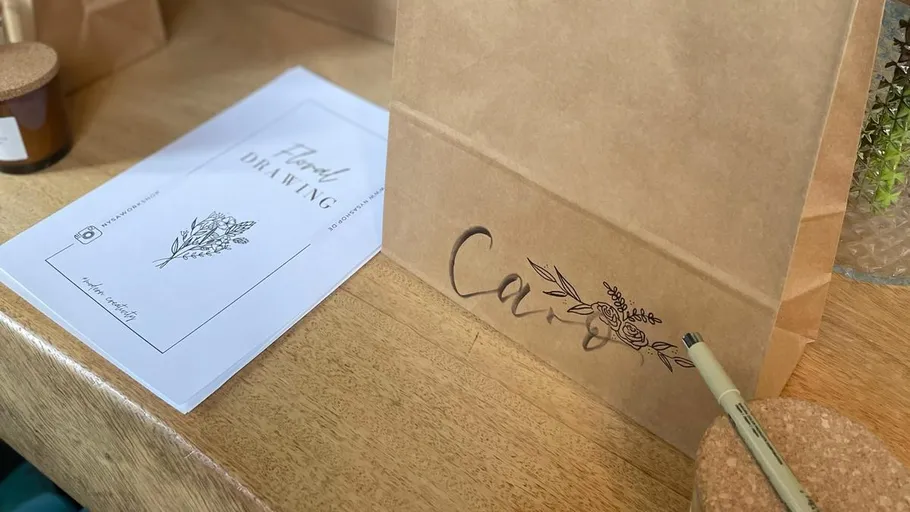 Papiertüte mit Blumendruck auf Tisch.