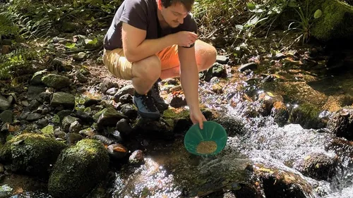 Man pans for gold in a creek.
