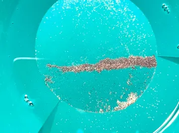 Gold particles in a blue pan.