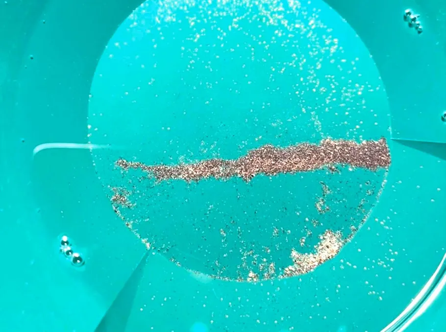 Goldpartikel in einer blauen Pfanne.