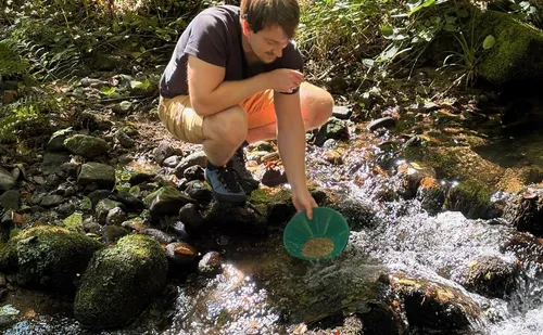 Mann sucht Gold in einem Bach.