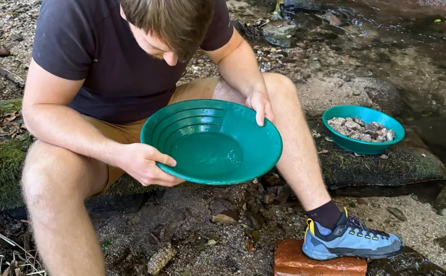 Man panning for gold by a small stream.