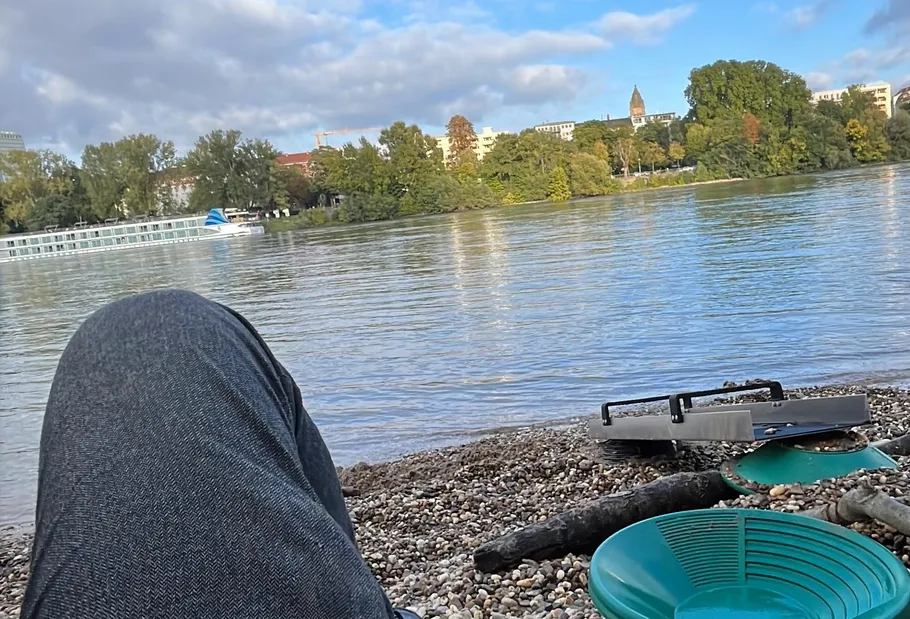 Person entspannt am Flussufer mit Pfannen daneben.