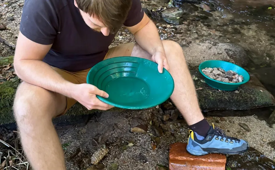 Man panning for gold by a stream.