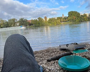 Person entspannt am Fluss mit Pfannenwerkzeugen.
