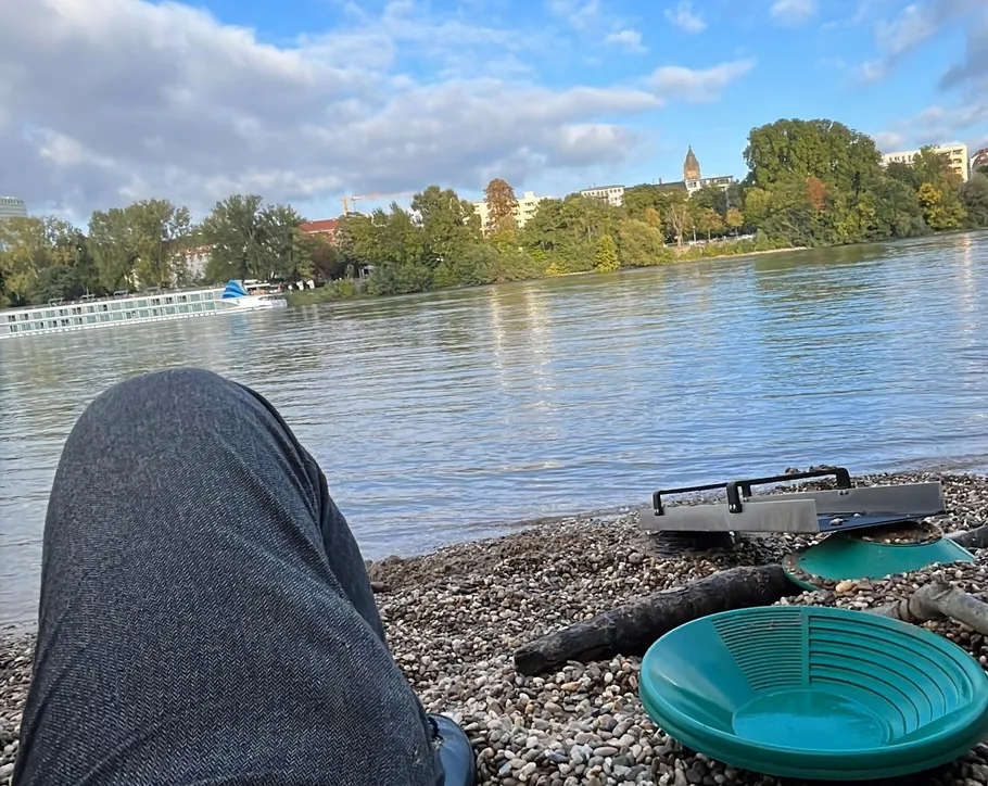 Person relaxing by river with pan tools.