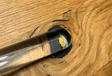 Test tube with substance on wooden surface.