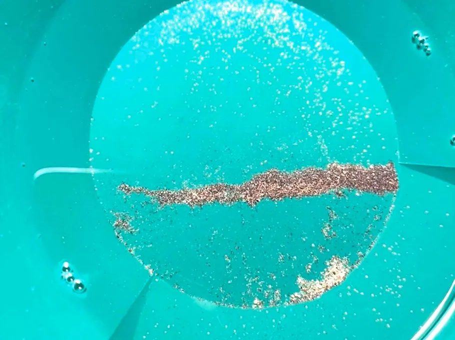 Gold flakes in a green pan.