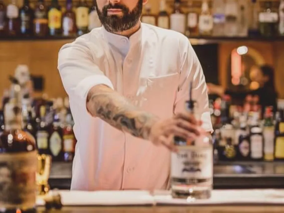 Bartender serves drinks at a well-stocked bar.