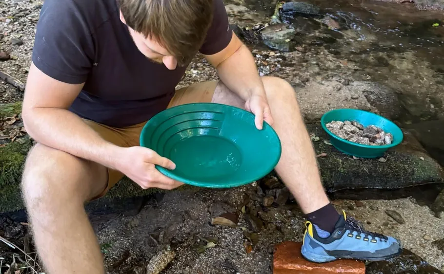 Man panning for gold by a stream.