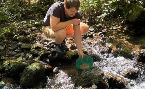 Person panning for gold in a stream.