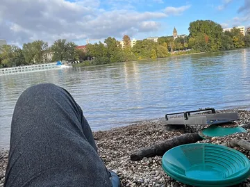 Person sitzt am Fluss mit Bergbauwerkzeugen.