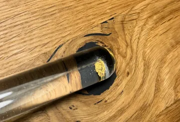Glass vial with gold powder on wood surface.