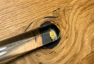 Goldstaub in Glastube auf Holztisch.