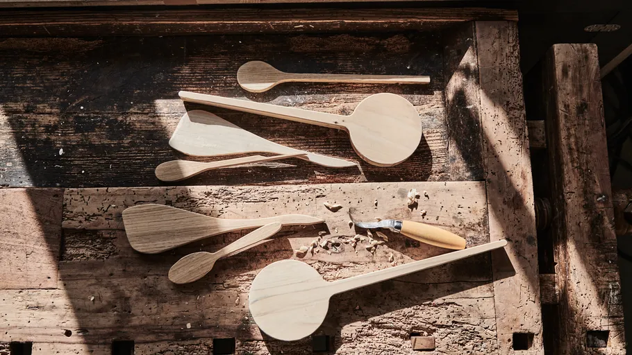 Wooden spoons and carving knife on workbench.