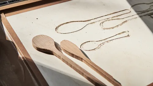 Wooden spoons on a workbench with cutouts.