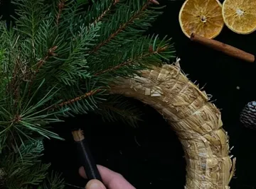 Green wreath is decorated with citrus and cinnamon.