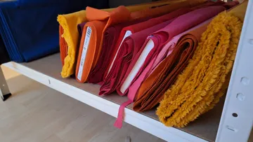 Colorful fabric rolls on a wooden shelf.