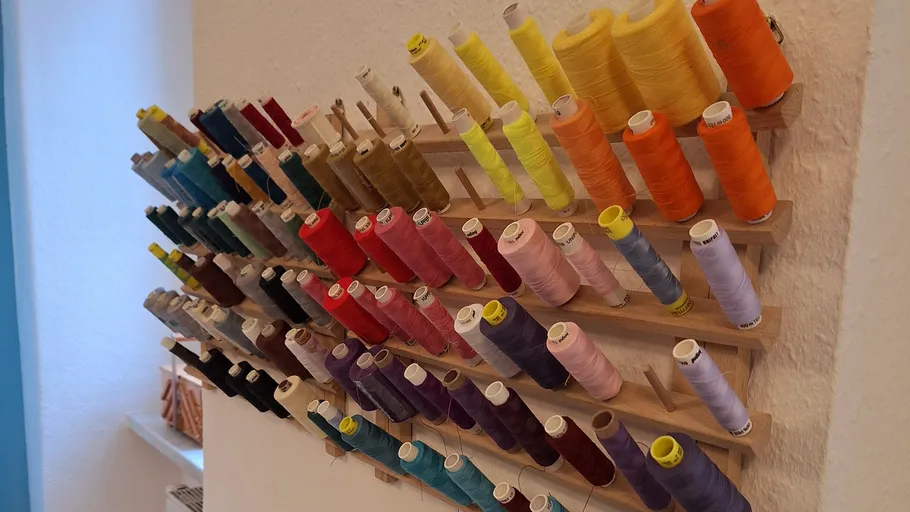 Colorful threads organized on a wall rack.