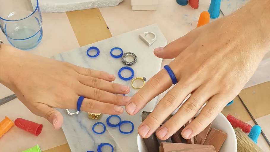 Hände mit blauen Ringen, umgeben von Werkzeugen.