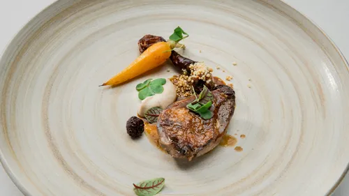 Gourmet dish with meat, carrot, and garnish.