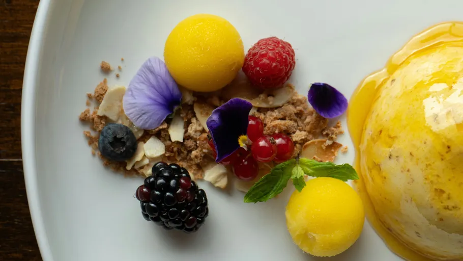 Buntes Dessert mit Früchten und violetten Blumen.
