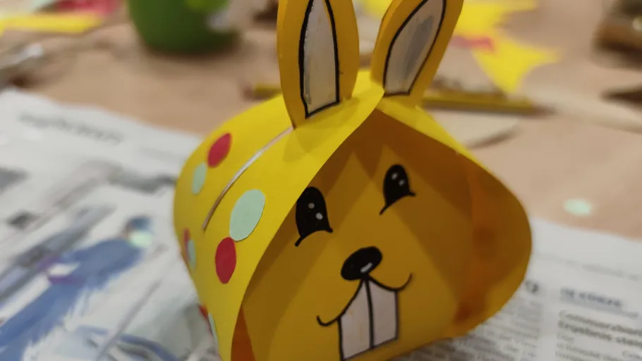 Yellow paper rabbit craft on a newspaper.