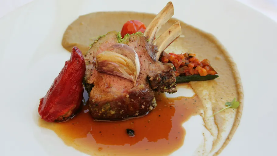 Lammkotelett mit Soße, Gemüse und Püree auf Teller.