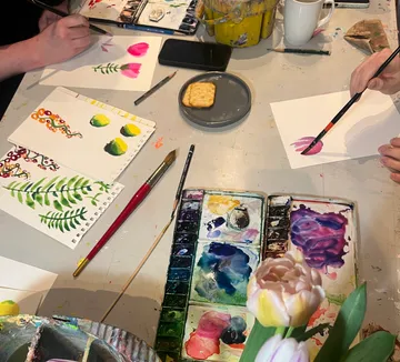 People painting flowers at a table.