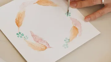 Hand painting watercolor feathers on paper.