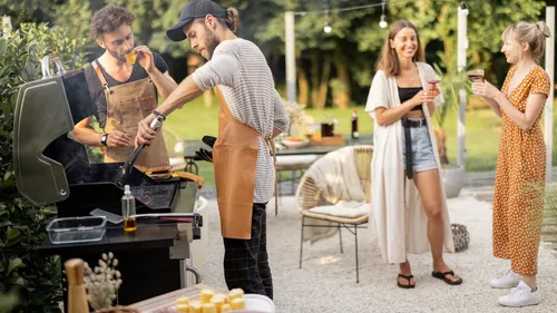 Two men grilling, two women chatting outdoors.
